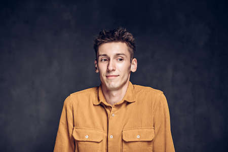 Young man with shrug gesture on dark backgroundの写真素材