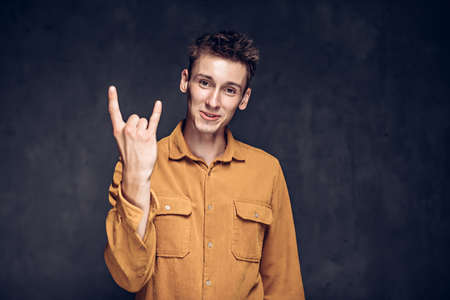 caucasian man show rock gesture on dark backgroundの写真素材