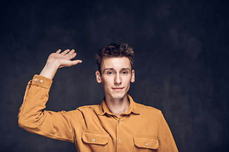young man show hello gesture on dark backgroundの写真素材