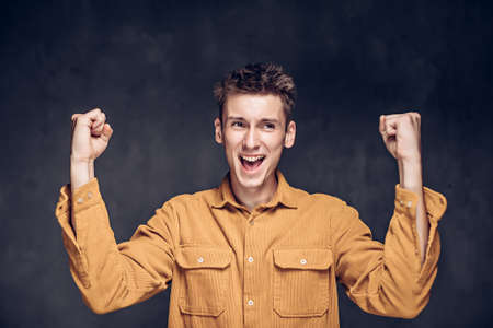 young man with success gesture on dark backgroundの写真素材