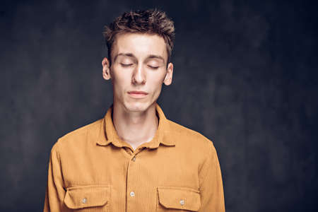 caucasian man with closed eyes on dark backgroundの写真素材