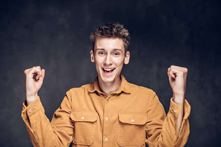 young man with success gesture on dark backgroundの写真素材