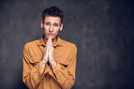 young man with please gesture on dark backgroundの写真素材