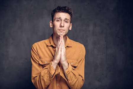 young man with please gesture on dark backgroundの写真素材
