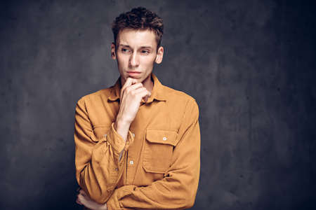 Thoughtful young caucasian man on dark backgroundの写真素材