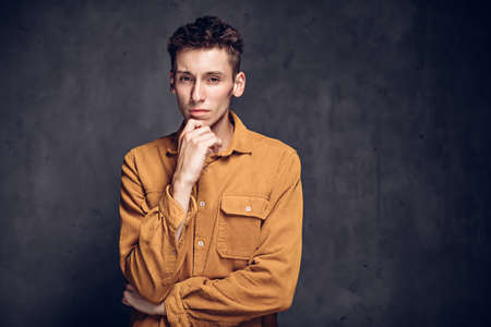 Thoughtful young caucasian man on dark backgroundの写真素材