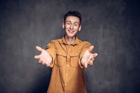 young man outstretched hands on dark backgroundの写真素材