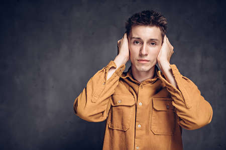 caucasian man covering ears on dark backgroundの写真素材
