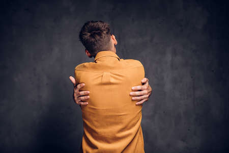 Back view of man clenched hands on dark backgroundの写真素材