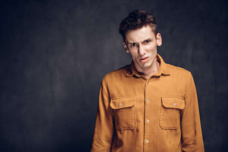 Dissatisfied young caucasian man on dark backgroundの写真素材