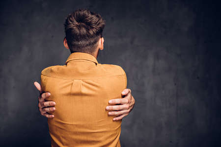 Back view of man clenched hands on dark backgroundの写真素材
