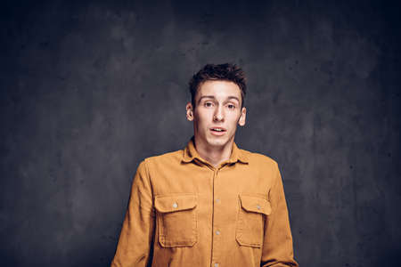 Scared young caucasian man on dark backgroundの写真素材