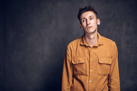 Sad young caucasian man on dark backgroundの写真素材