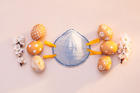 Easter eggs with flowering apricot branches and a protective maskの写真素材
