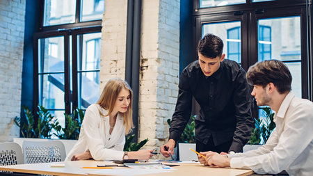 Businessman showing graph to colleagues in officeの写真素材