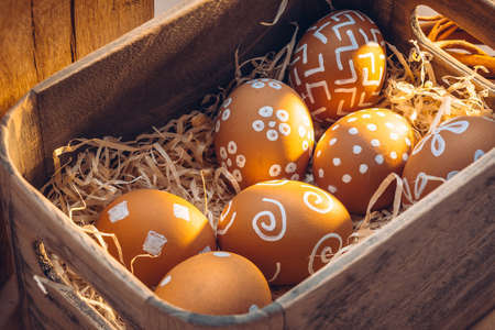 Easter in the countryside. Natural textures of farm with warm sunlight hues. Brown eggs with white patternsの写真素材