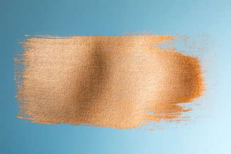 Golden paint brush stroke on blue paperの写真素材