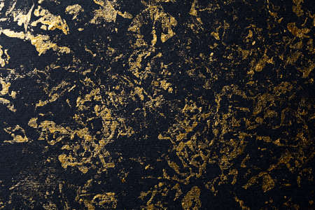 Abstract gold paint on black textured paperの写真素材