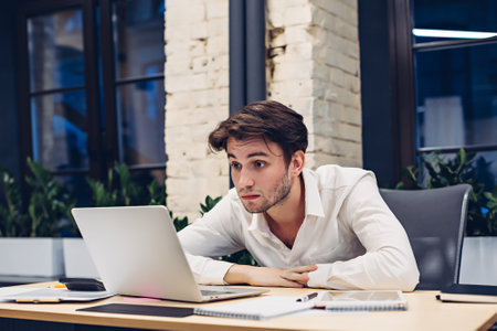 Surprised businessman working on laptop in officeの写真素材
