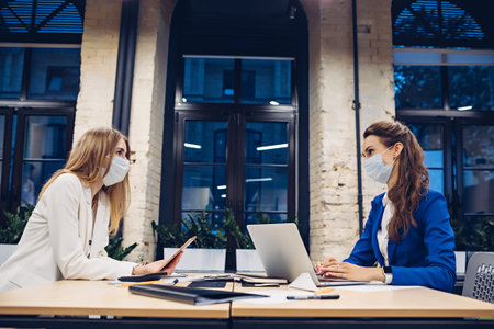 Businesswomen in medical masks working in office