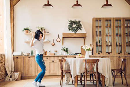 A young girl performs a joyful victory dance in the middle of the kitchen at homeの写真素材