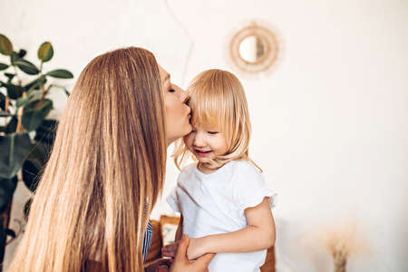 Young mom kissing her little child at homeの写真素材