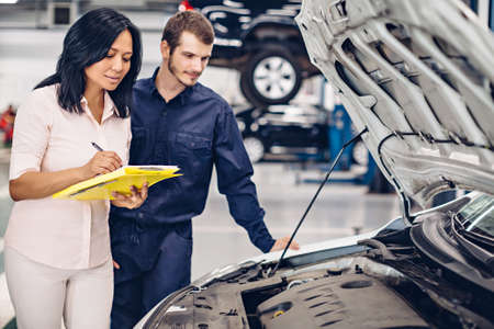 Auto car repair service center. The mechanic communicates with the clientの写真素材