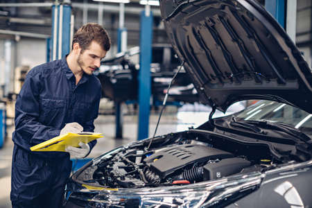 Auto car repair service center. Mechanic examining car engineの写真素材
