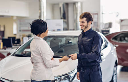 Car service center scene. The mechanic giving car key to the clientの写真素材