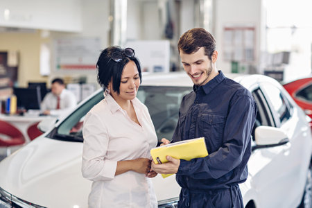 Car service center scene. The mechanic communicates with the clientの写真素材