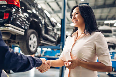 Car service center scene. The mechanic handshakes with the clientの写真素材