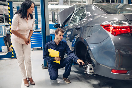 Auto car repair service center. A female customer and mechanic checking car breaksの写真素材