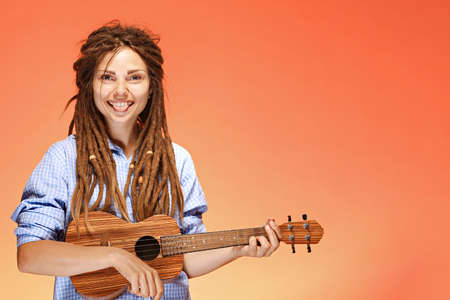 Portrait of funny young woman playing ukulele. Happiness and carefree conceptの写真素材