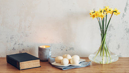 Easter eggs, bible and spring flowers on table against wall backgroundの写真素材