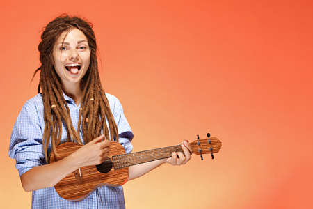 Portrait of funny young woman playing ukulele. Happiness and carefree conceptの写真素材