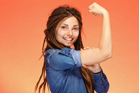 Smiling young woman showing her bicep. Girl power conceptの写真素材