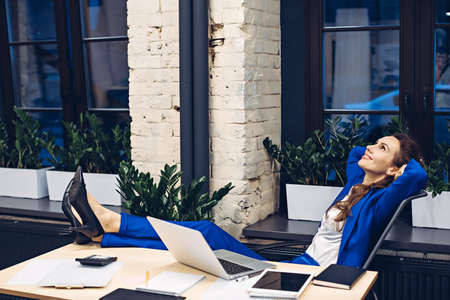 businesswoman relaxing on chair in officeの写真素材