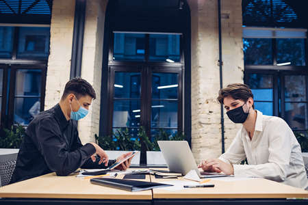 Businessmen in medical masks working in officeの写真素材