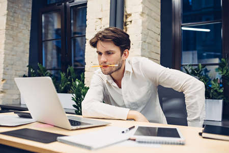 Focused businessman working on laptop in officeの写真素材