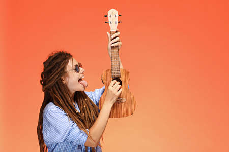 Portrait of funny young woman playing ukulele. Happiness and carefree conceptの写真素材