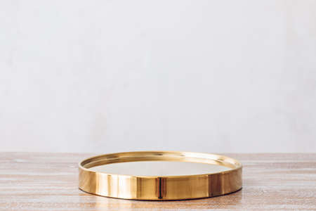 Golden product podium on wooden table on light wall backgroundの写真素材