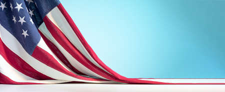 United States of America flag on white table on blue sky background. Celebration of the Fourth of July or US Independence Day backdropの写真素材