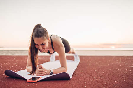 Young sportswoman doing exercise in plank position on the beachの写真素材