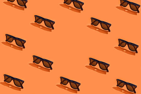 Black sunglasses on orange. Halloween or summer heat background with copy spaceの写真素材
