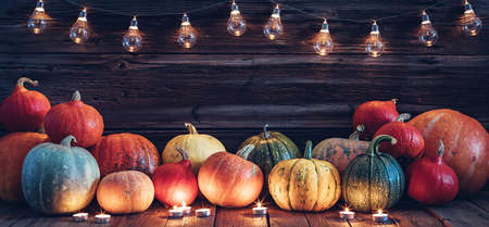 Halloween background decorated with pumpkins, lights and candles. Wooden wall with copy spaceの写真素材