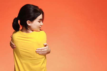 Happy young woman hugging herselfの写真素材