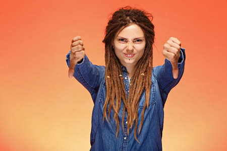 Young woman with both hands shows a dislike gesture and laughsの写真素材