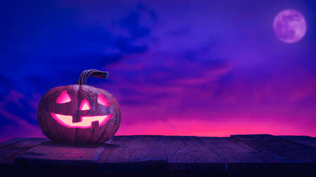 Halloween pumpkin jack o lantern on wood planks against pink and blue sky with moonの写真素材