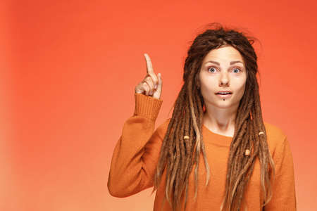 A young woman who invented a good idea. Raising index finger up with surprised faceの写真素材