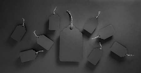 Black tags on black. Biggest one and many small. Black friday background with copy spaceの写真素材
